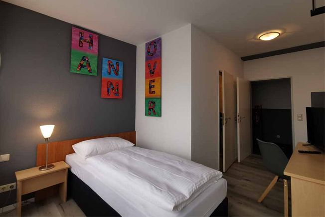 Standard-Zimmer mit Einzelbett, Nachttisch und Fernseher im Budget Hotel in Hannover